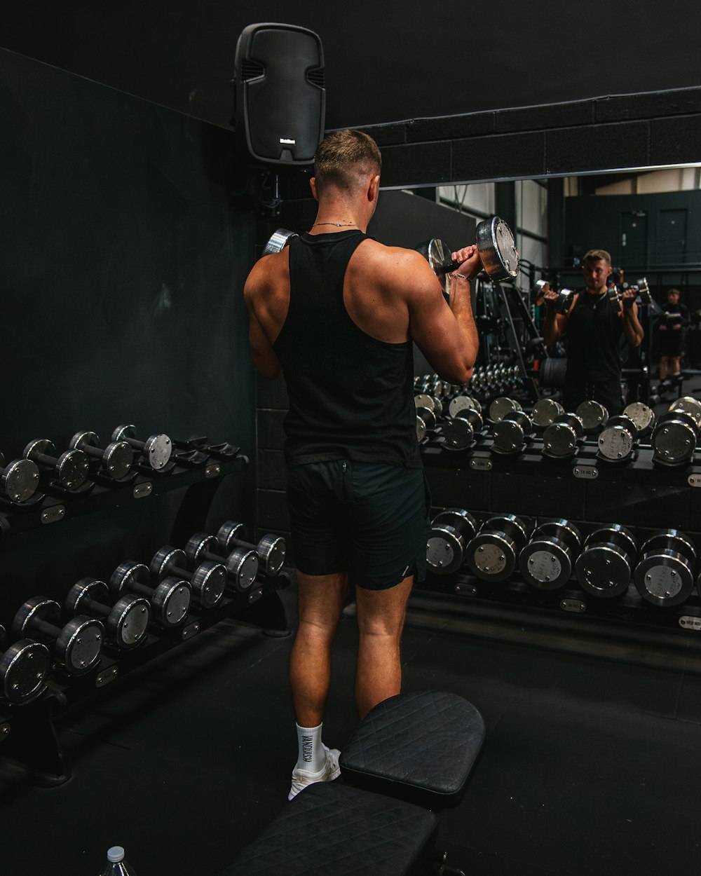 Athlete performing a bicep curl in a dark gym